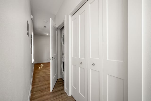 hall featuring stacked washer / drying machine and hardwood / wood-style floors