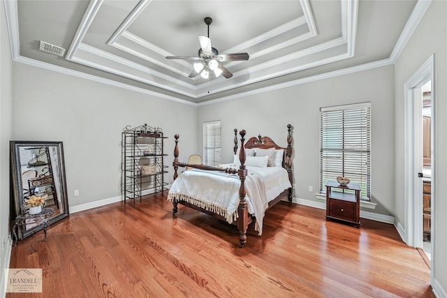 bedroom with hardwood / wood-style flooring, ceiling fan, and a raised ceiling