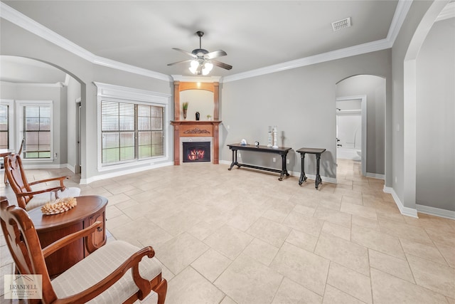 living room featuring a fireplace, ceiling fan, and crown molding