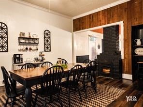 dining space featuring hardwood / wood-style floors, wooden walls, and crown molding