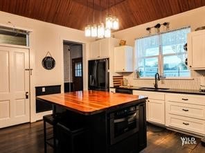 kitchen featuring a kitchen island, black fridge, and white cabinets