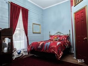 bedroom featuring wood walls and crown molding