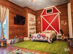 bedroom with wooden walls and hardwood / wood-style floors