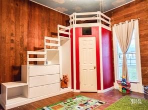 unfurnished bedroom featuring hardwood / wood-style flooring and wooden walls