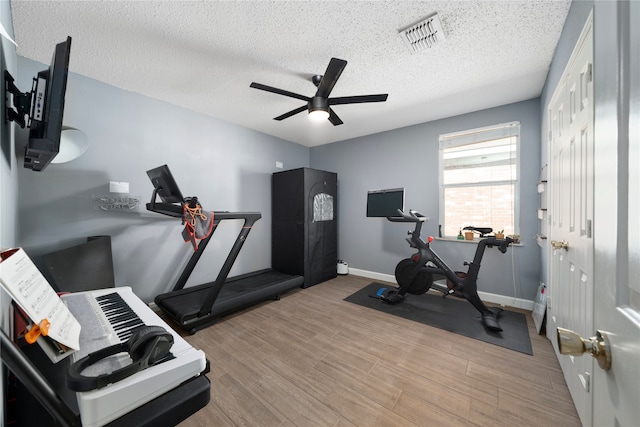 workout area with ceiling fan, a textured ceiling, and light wood-type flooring