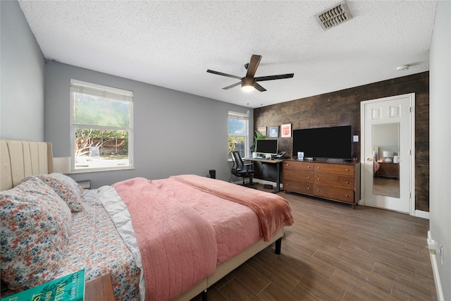 bedroom with hardwood / wood-style flooring, ceiling fan, wooden walls, and multiple windows