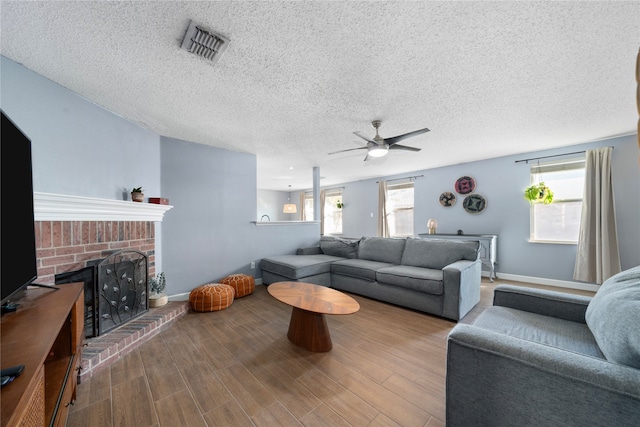 living room with a fireplace, ceiling fan, hardwood / wood-style floors, and a textured ceiling