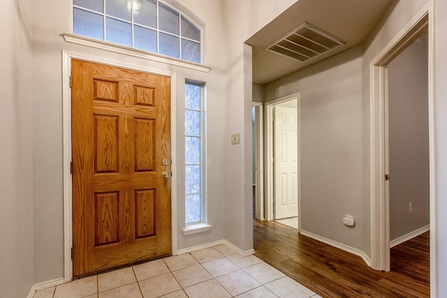 foyer featuring light tile patterned floors, baseboards, and visible vents