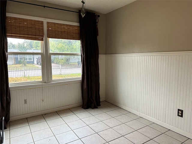 spare room featuring light tile patterned flooring and a textured ceiling