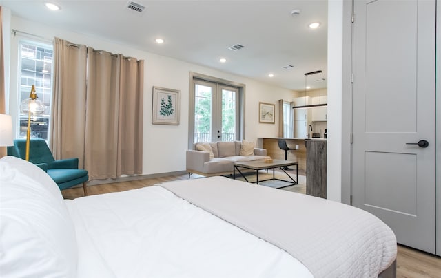 bedroom with french doors and light hardwood / wood-style flooring