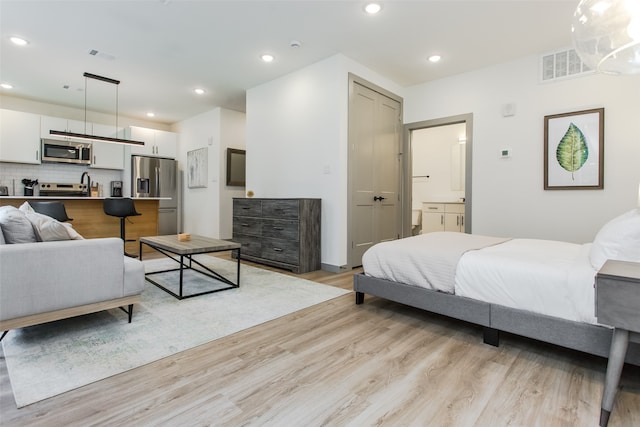 bedroom featuring stainless steel refrigerator with ice dispenser and light hardwood / wood-style flooring