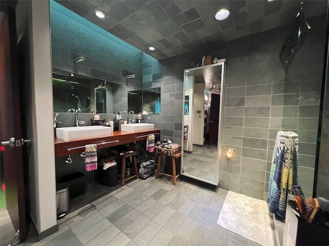 bathroom featuring walk in shower, vanity, and tile walls