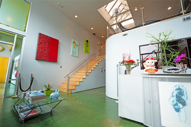 interior space featuring a towering ceiling, a skylight, and concrete floors