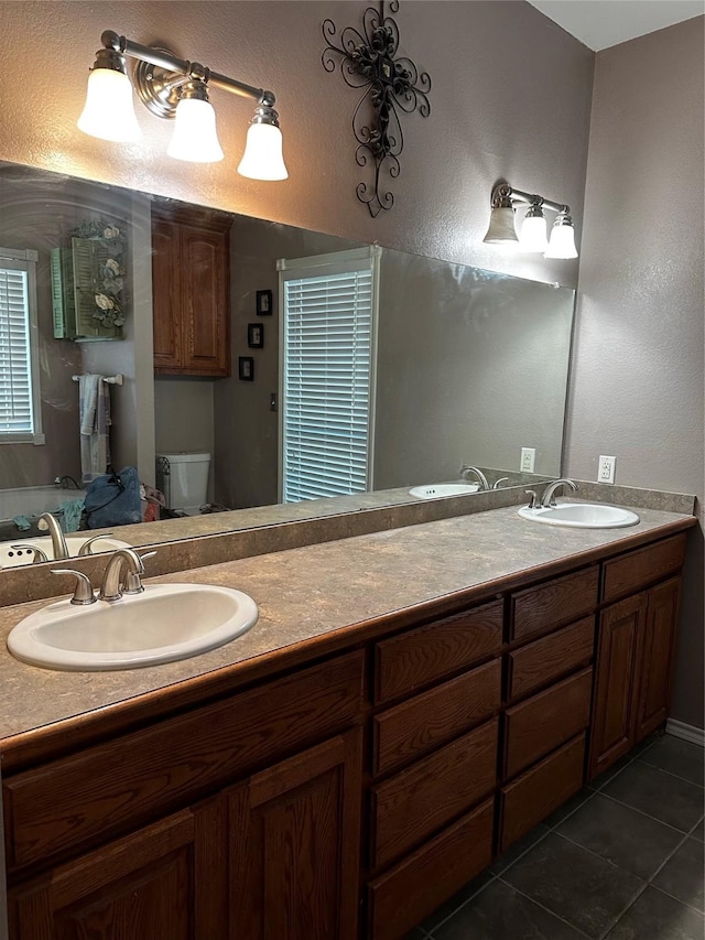 bathroom featuring double vanity, a sink, toilet, and tile patterned floors