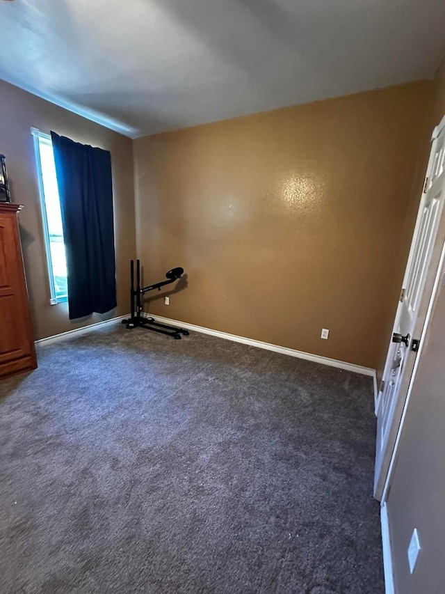 interior space with baseboards and dark carpet