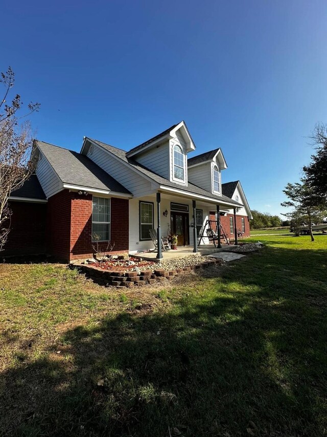 view of front of home featuring covered porch and a front lawn