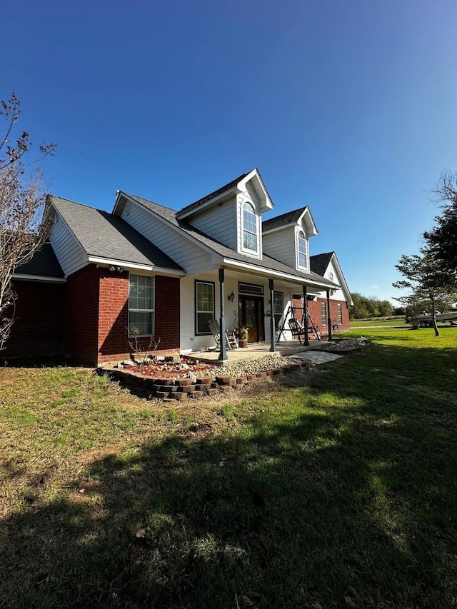 view of side of home featuring covered porch, brick siding, and a lawn