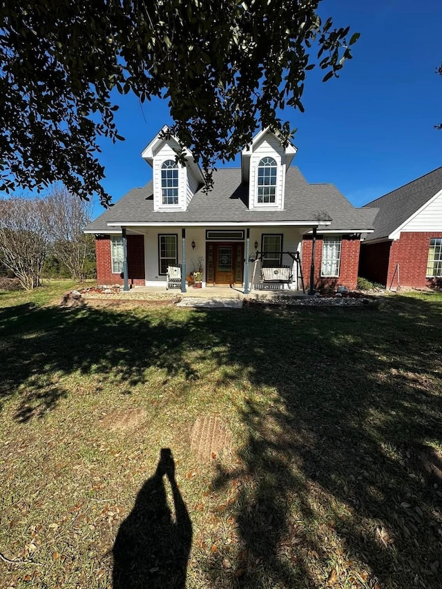 view of front of home featuring a porch, brick siding, and a front lawn