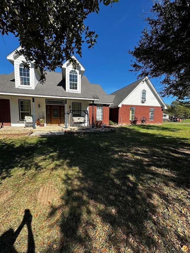 cape cod-style house with a porch, a front yard, and brick siding