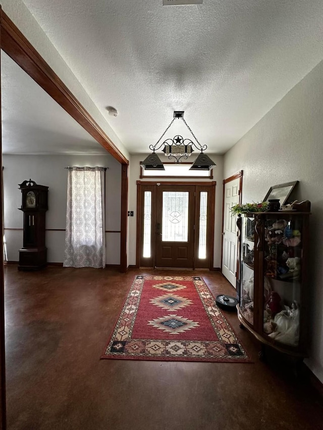 foyer featuring a textured wall, dark carpet, and a textured ceiling