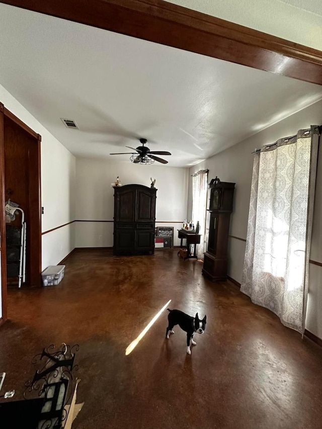 unfurnished living room featuring finished concrete flooring, ceiling fan, visible vents, and baseboards