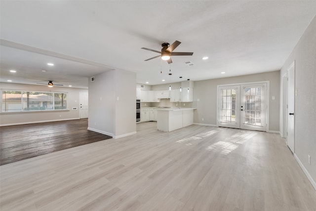 unfurnished living room with ceiling fan, plenty of natural light, light wood-type flooring, and french doors