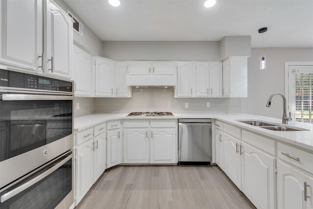 kitchen with white cabinetry, stainless steel appliances, sink, and decorative light fixtures