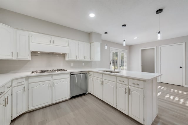 kitchen featuring stainless steel appliances, light hardwood / wood-style floors, sink, kitchen peninsula, and pendant lighting