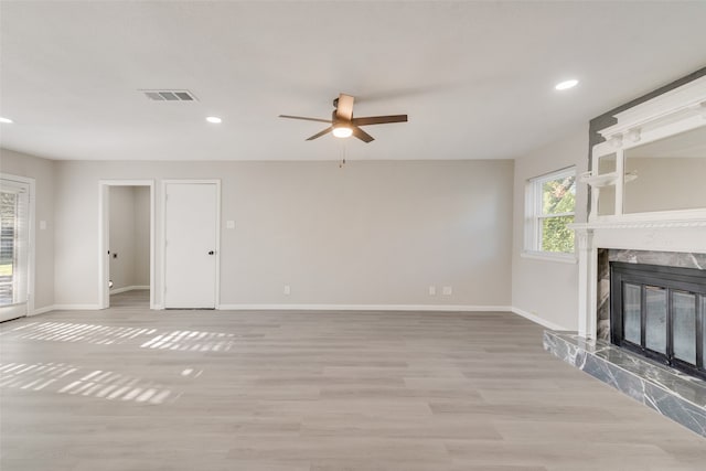 unfurnished living room with light hardwood / wood-style flooring, ceiling fan, and a high end fireplace