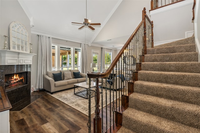 living room with ornamental molding, ceiling fan, high vaulted ceiling, a tile fireplace, and dark hardwood / wood-style flooring