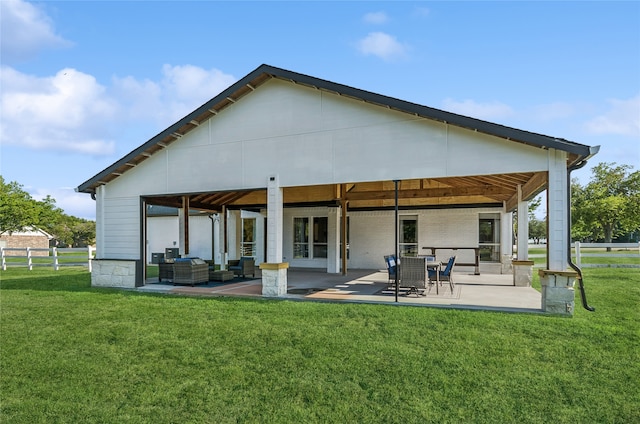 rear view of house with outdoor lounge area, a lawn, and a patio area