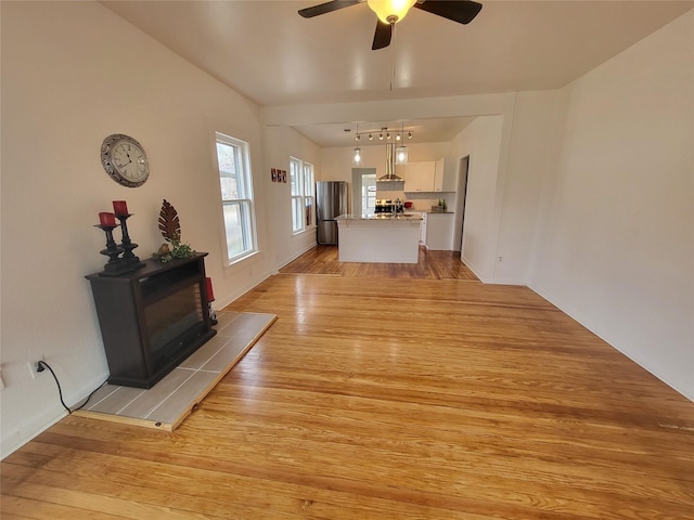 unfurnished living room with ceiling fan, light wood-type flooring, and vaulted ceiling