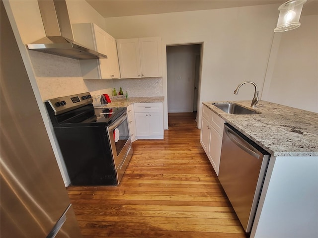 kitchen with white cabinetry, appliances with stainless steel finishes, hanging light fixtures, sink, and wall chimney exhaust hood