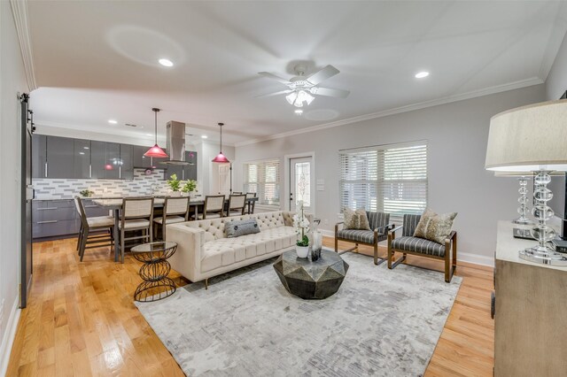 dining area with light wood-type flooring, a barn door, ornamental molding, and sink