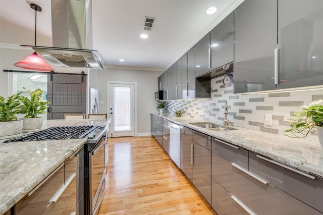 kitchen with light stone countertops, island range hood, stainless steel appliances, and sink