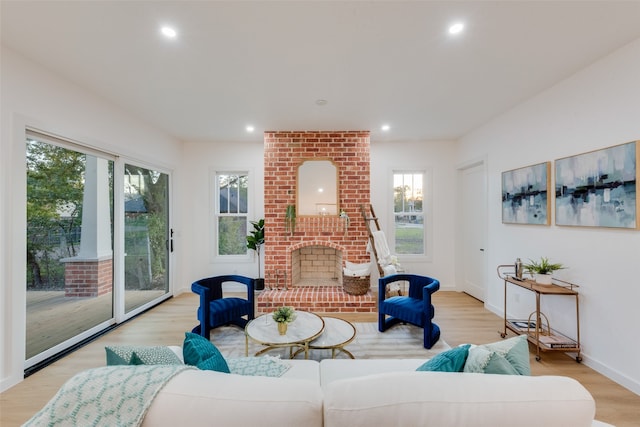 living room featuring a brick fireplace and light hardwood / wood-style flooring