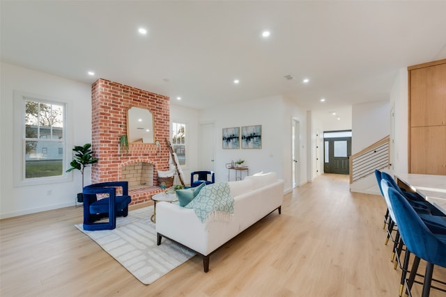 living room with a brick fireplace and light hardwood / wood-style flooring