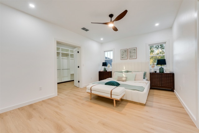 bedroom featuring a closet, a spacious closet, ceiling fan, and light hardwood / wood-style flooring