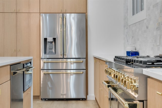 kitchen featuring light hardwood / wood-style flooring, tasteful backsplash, light brown cabinetry, and stainless steel appliances