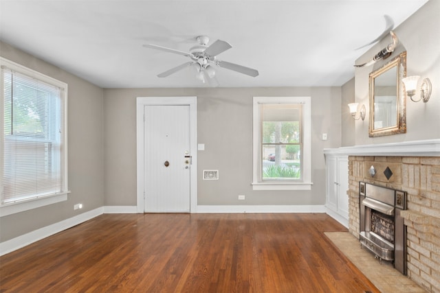 unfurnished living room featuring dark hardwood / wood-style flooring, ceiling fan, and a brick fireplace