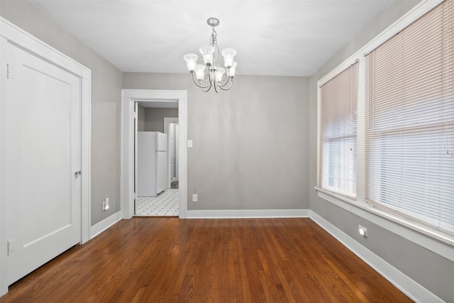 spare room featuring dark hardwood / wood-style floors and a chandelier