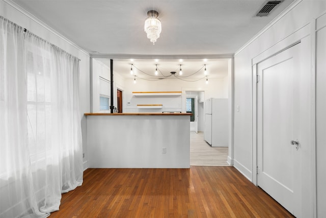 kitchen featuring light hardwood / wood-style floors, white refrigerator, and a notable chandelier