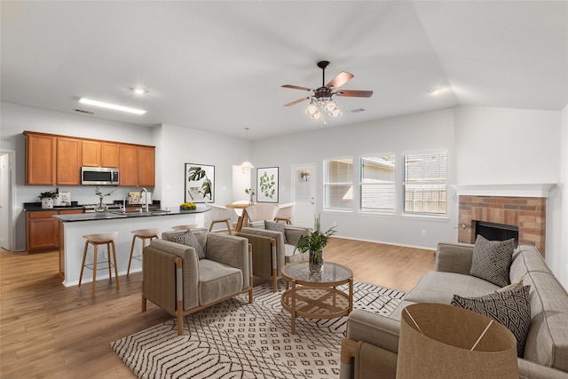 living room featuring ceiling fan, a fireplace, light hardwood / wood-style floors, and lofted ceiling