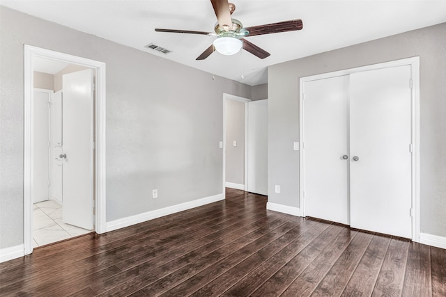 unfurnished bedroom with dark wood-type flooring, ceiling fan, and a closet