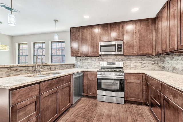 kitchen featuring stainless steel appliances, backsplash, hanging light fixtures, sink, and dark wood-type flooring