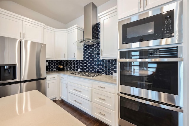 kitchen with dark wood-type flooring, wall chimney range hood, appliances with stainless steel finishes, and white cabinets