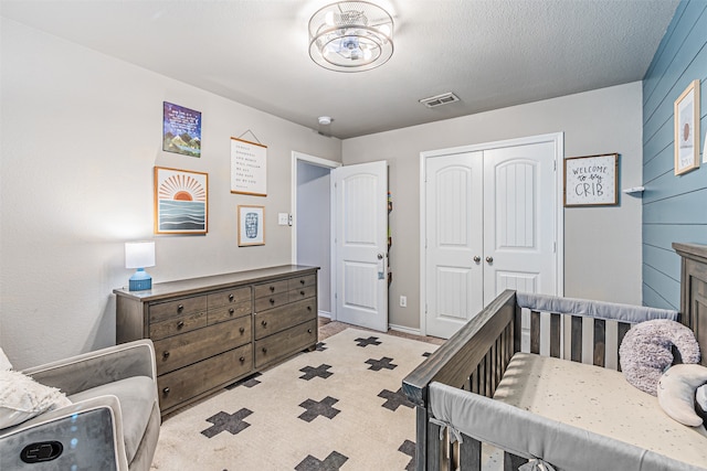 bedroom with a textured ceiling, a closet, and a nursery area