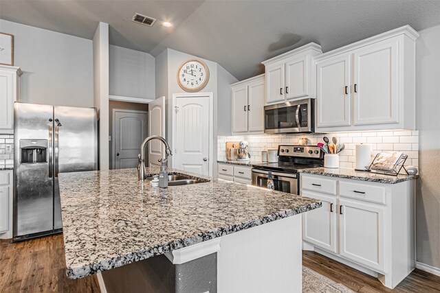 kitchen with white cabinets, hardwood / wood-style flooring, sink, a kitchen island with sink, and appliances with stainless steel finishes