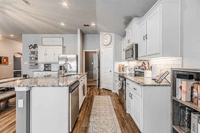 kitchen with dark hardwood / wood-style flooring, white cabinetry, appliances with stainless steel finishes, and a kitchen island with sink