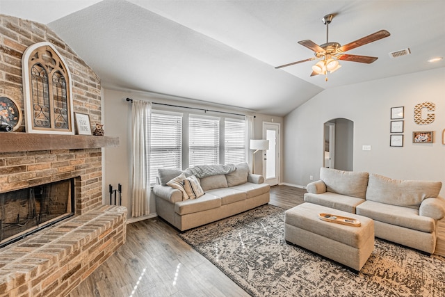 living room featuring a brick fireplace, hardwood / wood-style floors, ceiling fan, and vaulted ceiling